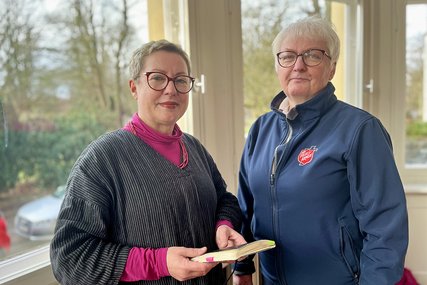 Pröpstin Petra Kallies (links) hält ein Buch in der Hand und Rosemarie Scharf stehen vor einem Fenster und schauen in die Kamera - Copyright: Bastian Modrow  